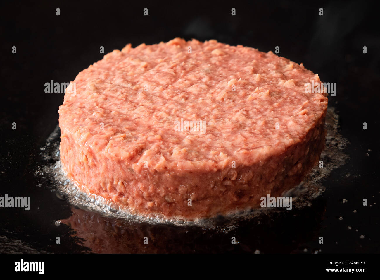 Burger végétarien à base de plantes non cuite patty être cuit sur une grille de fer noir. Banque D'Images