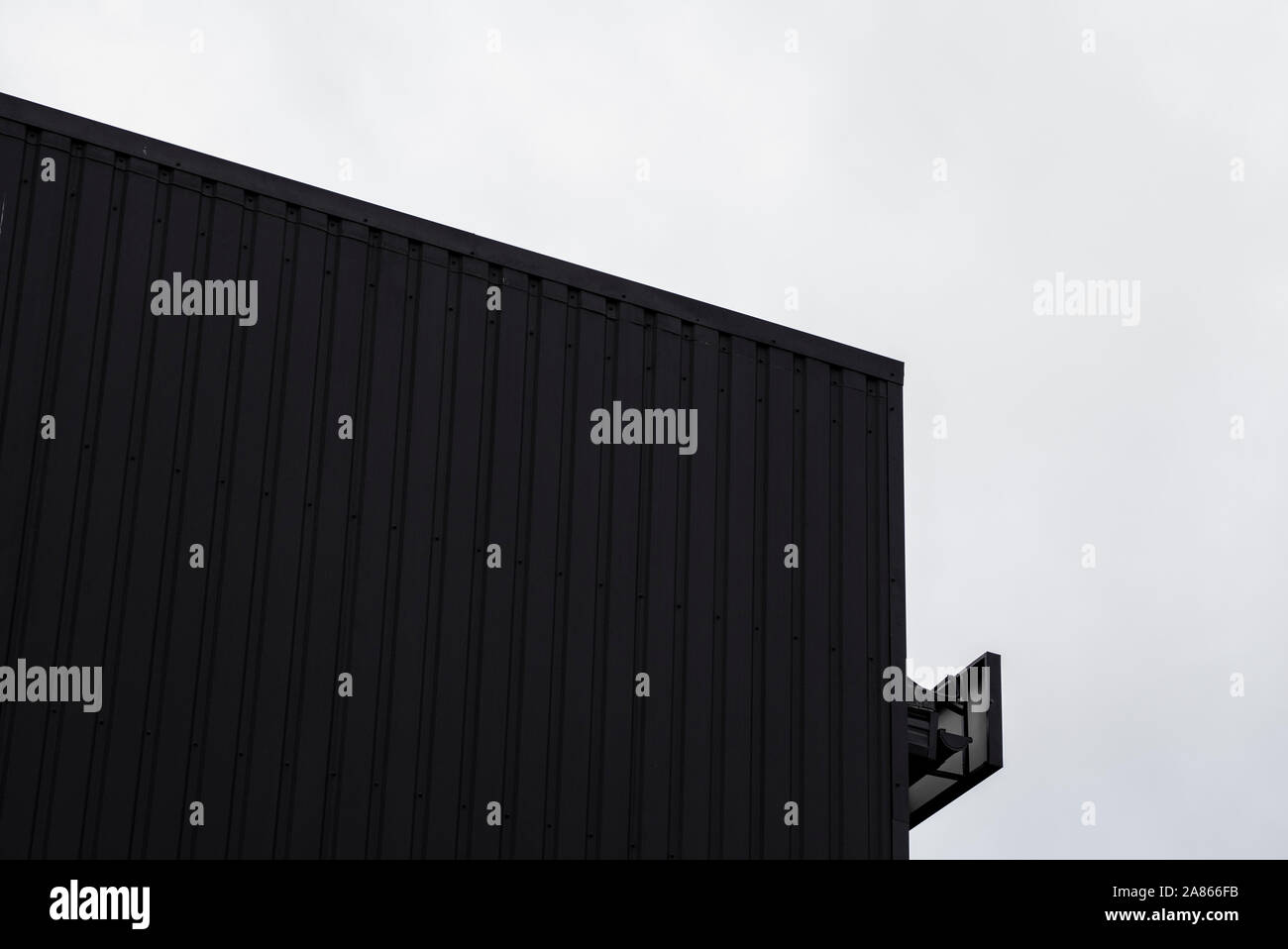 Noir et blanc surface texture feuille de métal ondulé sur la paroi d'un immeuble avec un ciel nuageux. Fond en acier galvaniser. Banque D'Images