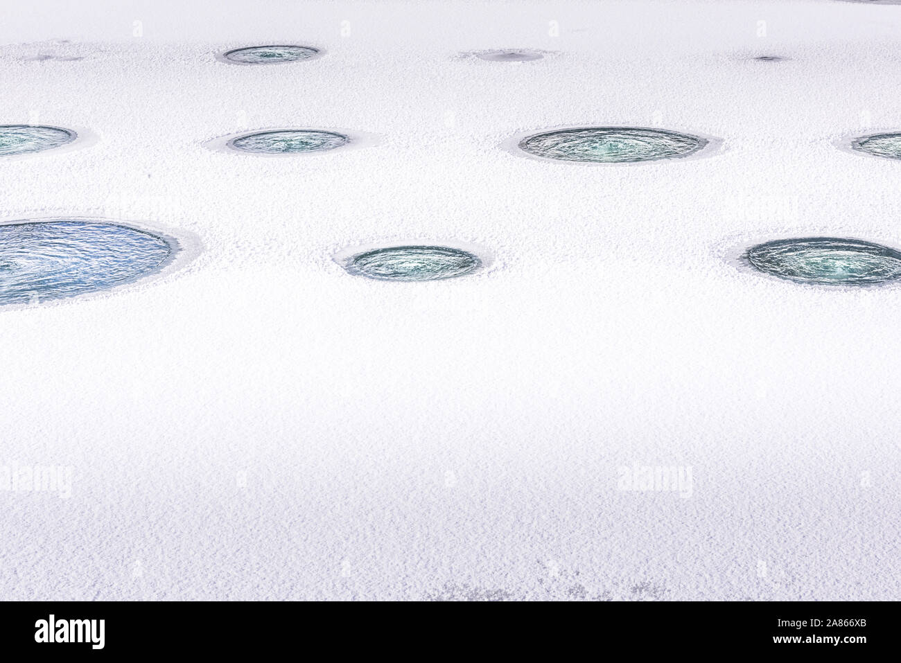 Les lignes horizontales de trous faits dans la glace, c'est portant sur l'étang du poisson aéré pendant la saison d'hiver, visant à protéger les populations de poisson. Arrière-plan de saison Banque D'Images