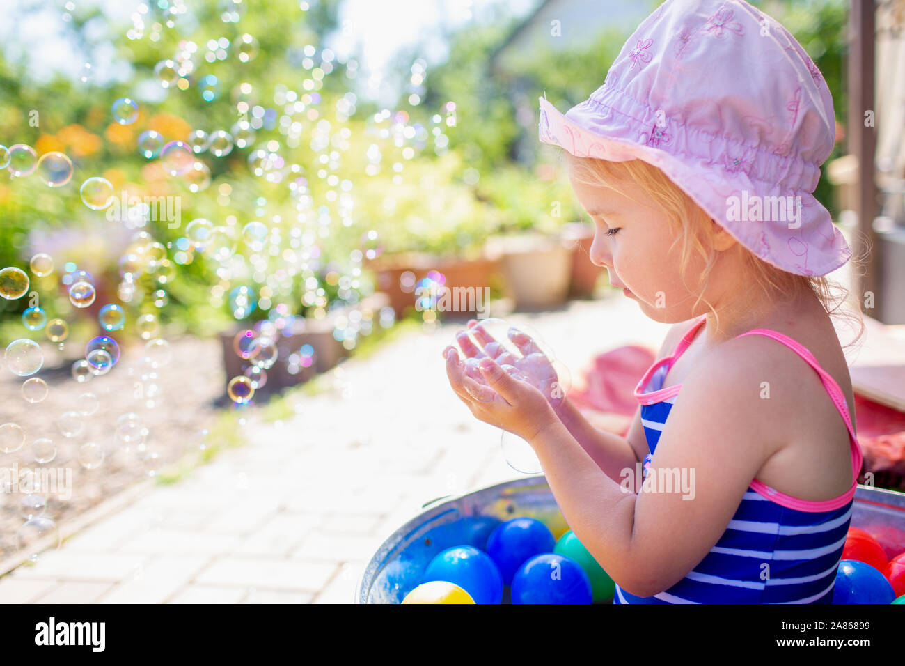 Adorable Blond Bebe Fille 3 Ans Dans Un Chapeau Rose Et Bleu Maillot De Bain Ayant Depouille A L Arriere Cour Et Jouer Avec Des Bulles Des Vacances D Ete Photo Stock Alamy
