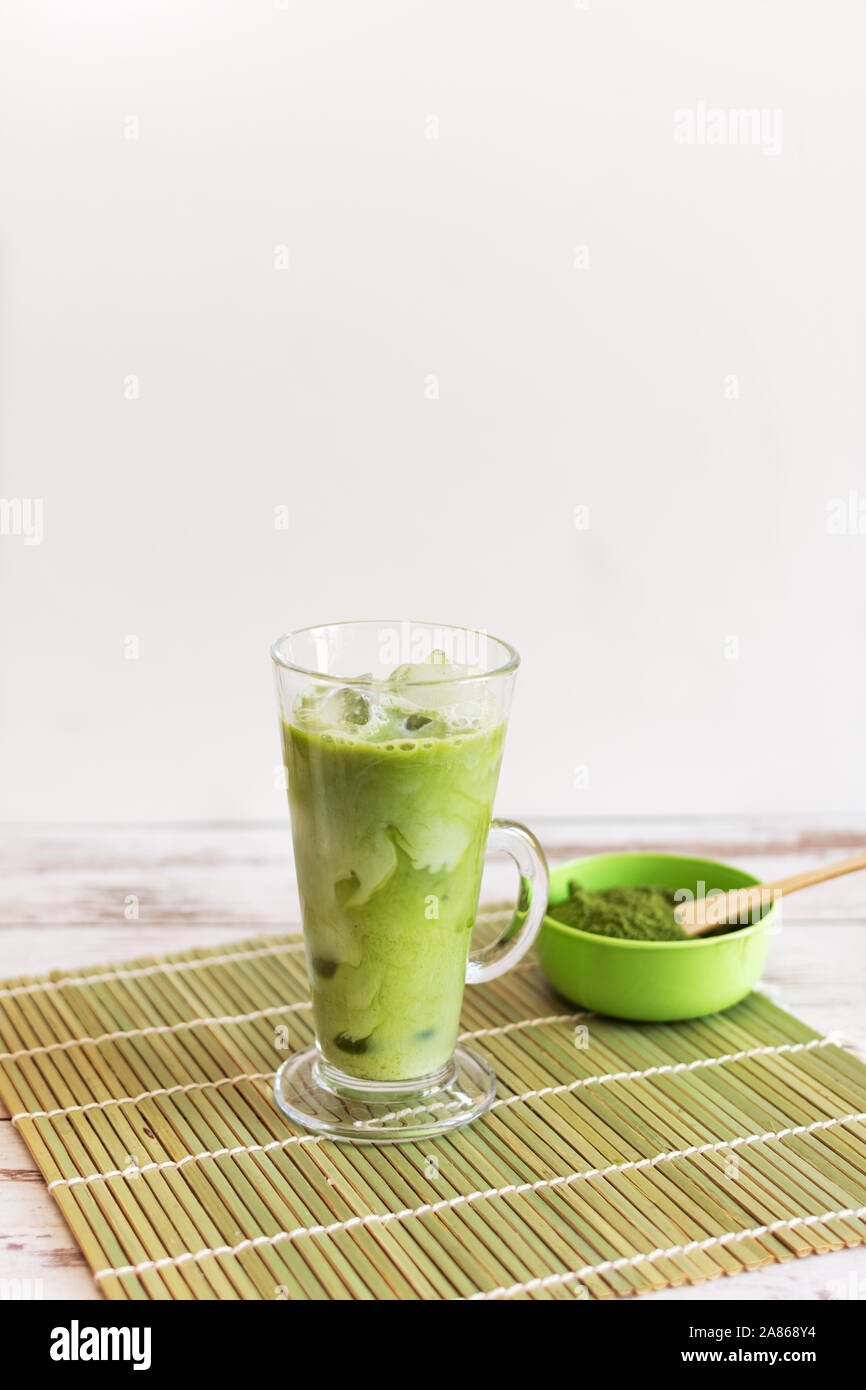 Matcha latte glacé dans un verre Tumbler glass avec le lait de coco verser de pitcher à la main, exemplaire de l'espace. Boissons rafraîchissantes d'été vegan boisson froide. Banque D'Images