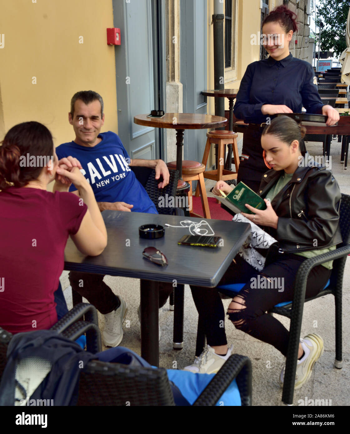 Les clients à la table dans le café on sert en serveuse, dans la vieille ville de Pula, Croatie Banque D'Images Les clients à la table dans le café on sert en serveuse, dans la vieille ville de Pula, Croatie Banque D'Images