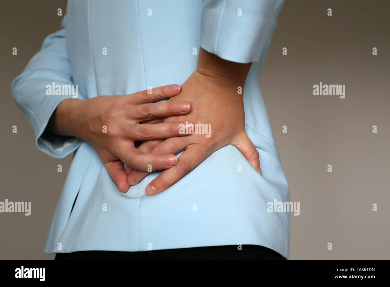 Dans la douleur, côté femme en costume de bureau souffrant de Mal de dos.  Les mains tenant le bas du dos, concept de maladie du rein ou de la colonne  vertébrale Photo