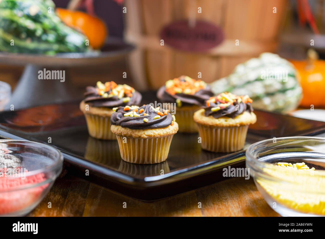 Le thème de l'automne mini cupcakes. Yellow cake au chocolat avec glaçage orange, rouge, jaune et paillettes. Cupcakes sur plaque carrée noire. Banque D'Images