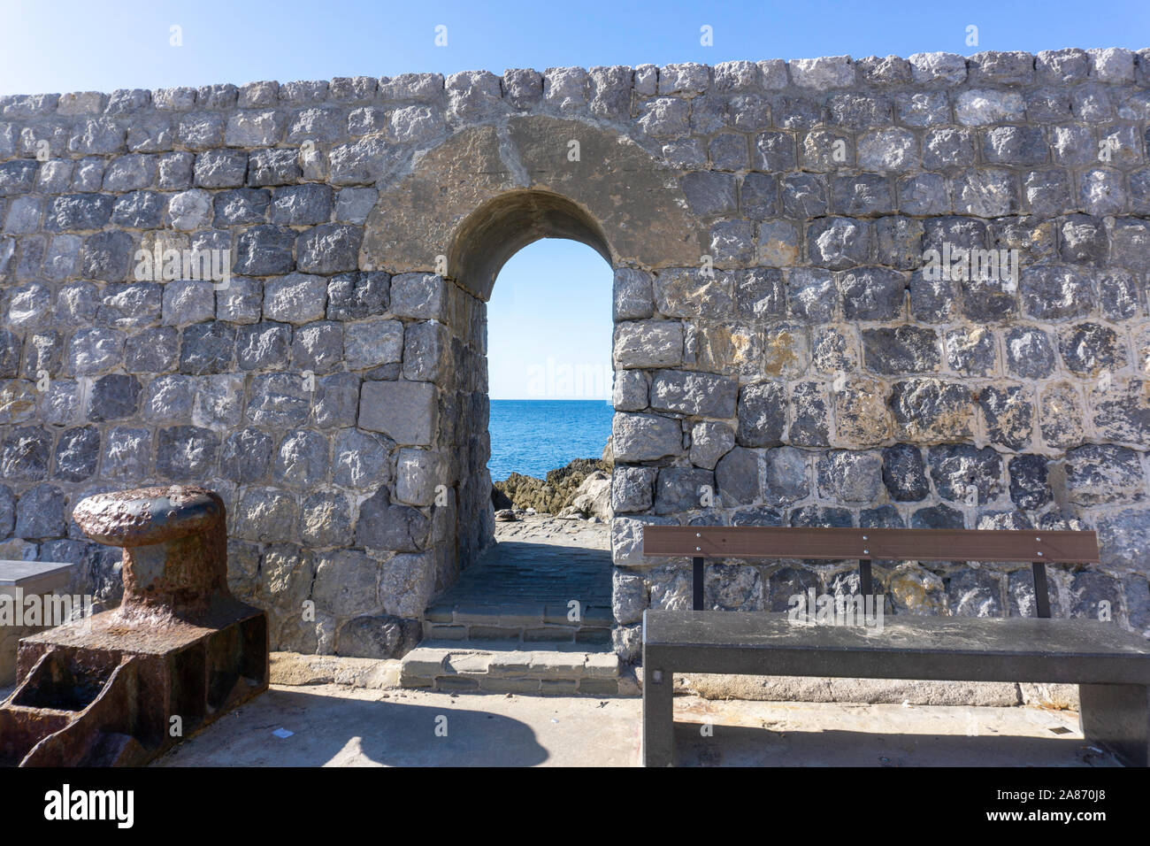 Sur la jetée de Cefalú, Sicile, Italie, un beau mur de pierre portant une arcade menant à la mer.avec un woo Banque D'Images
