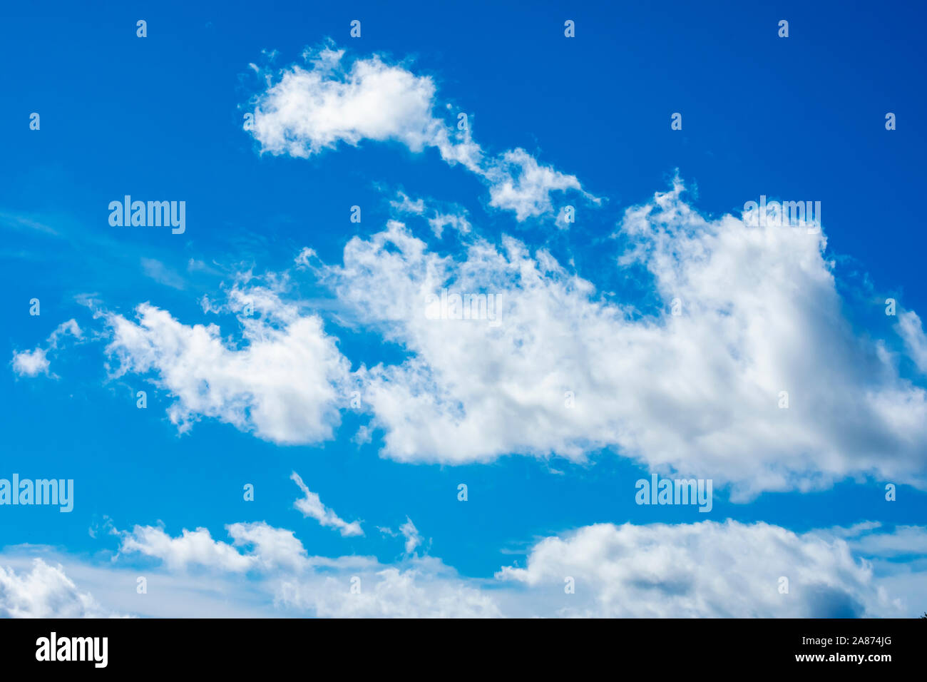 Dramatique nuages duveteux ensoleillée contre un ciel d'été bleu Banque D'Images