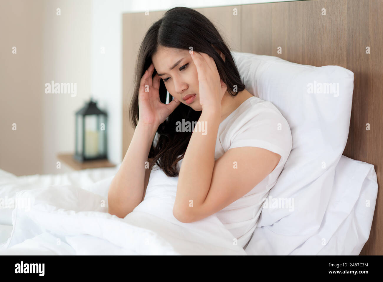 Young Asian woman service sur son lit tenant la main de maux de tête et à se sentir malheureux et mal de tête / migraines / stress / malades. Banque D'Images