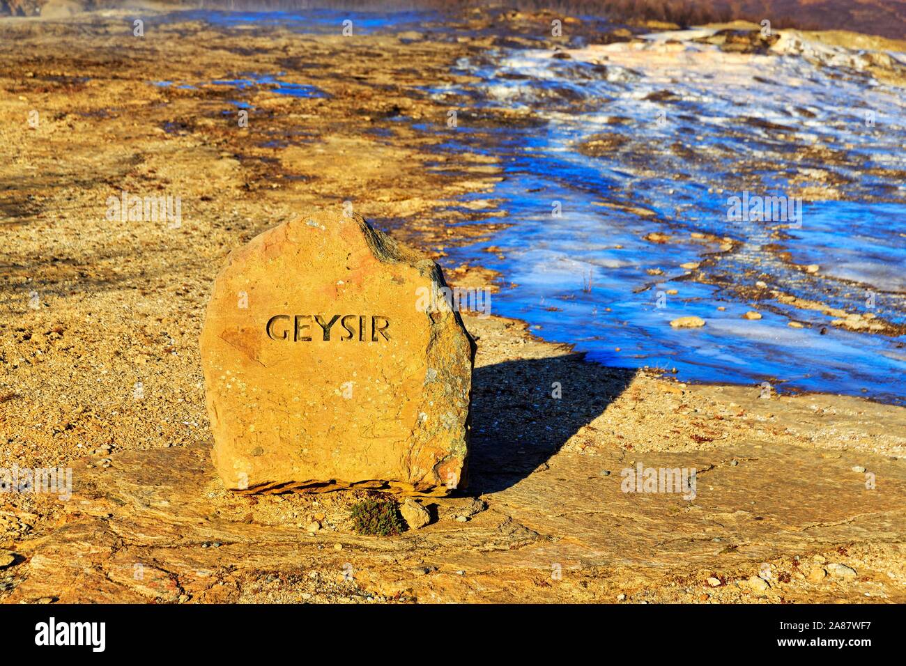 La pierre rouge avec l'inscription Geysir, à côté d'une surface d'eau gelés, zone à haute température, de Haukadalur, cercle d'Or le sud de l'Islande, Islande Banque D'Images