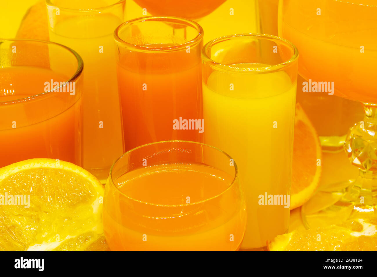 Composition abstraite de jus d'orange et de jaune en forme de boissons diverses lunettes avec des tranches de fruits orange et placés sur fond jaune avec l'exemplaire Banque D'Images