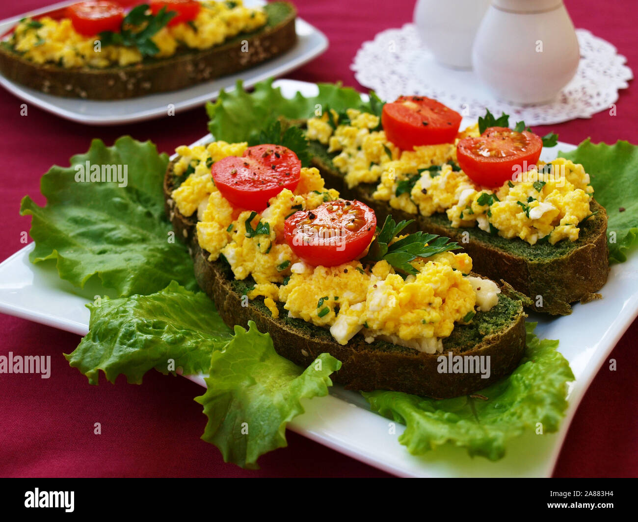 Des sandwichs avec des oeufs brouillés et tomates cerises sur du pain avec des orties Banque D'Images