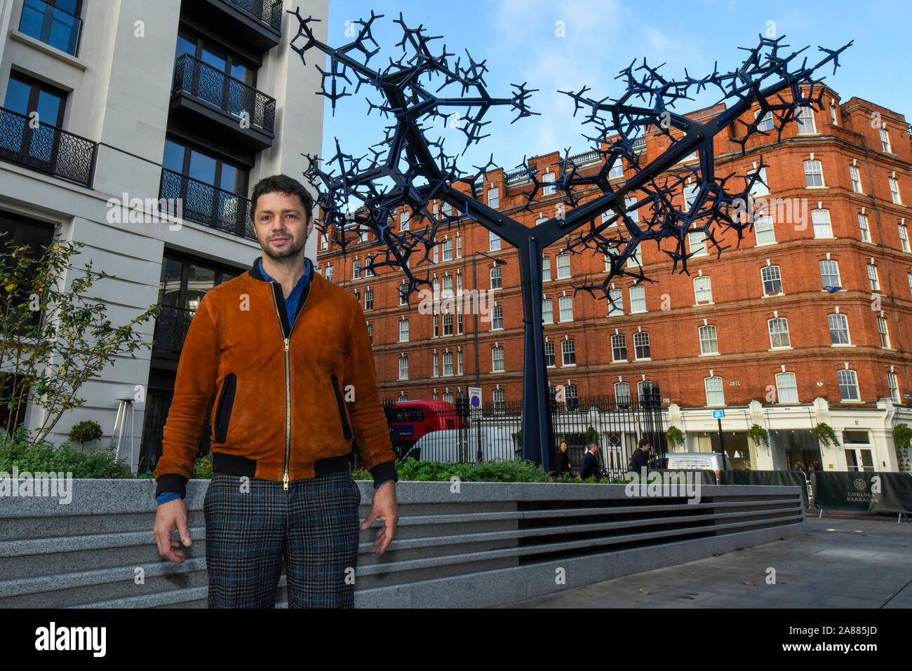 Londres, Royaume-Uni. 7 novembre 2019. Conrad Shawcross RA pose à côté de son nouveau travail' à 'régime bicaméral son dévoilement au Chelsea Barracks. Les 8m de hauteur sculpture est en aluminium anodisé formé de près de 700 composants et ressemblent à des systèmes naturels, y compris les voies nerveuses ou un arbre. schématisées C'est la première œuvre commandée pour Chelsea Barracks, quartier le plus récent. Crédit : Stephen Chung / Alamy Live News Banque D'Images