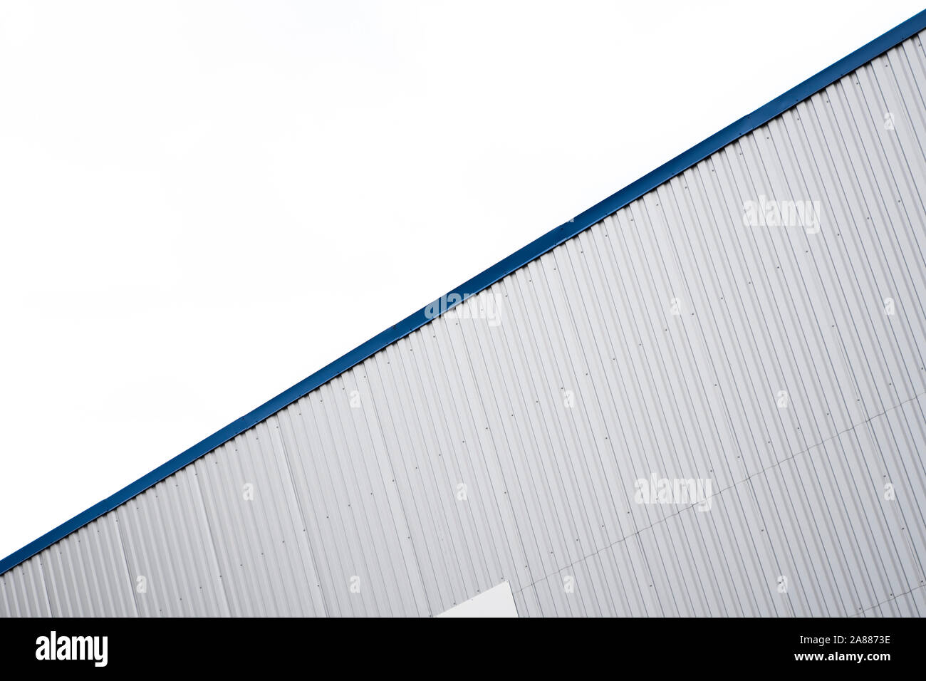 Plaques ondulées métalliques sur un bâtiment avec un bleu metal coins. Toit ondulé en aluminium blanc pour mur ou contre feuilles ciel nuageux sur l'arrière-plan Banque D'Images