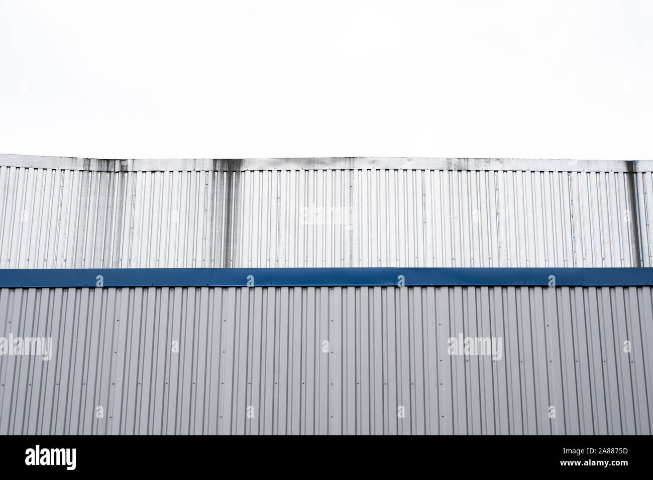 Plaques ondulées métalliques sur un bâtiment avec un bleu metal coins. Toit ondulé en aluminium blanc pour mur ou contre feuilles ciel nuageux sur l'arrière-plan Banque D'Images