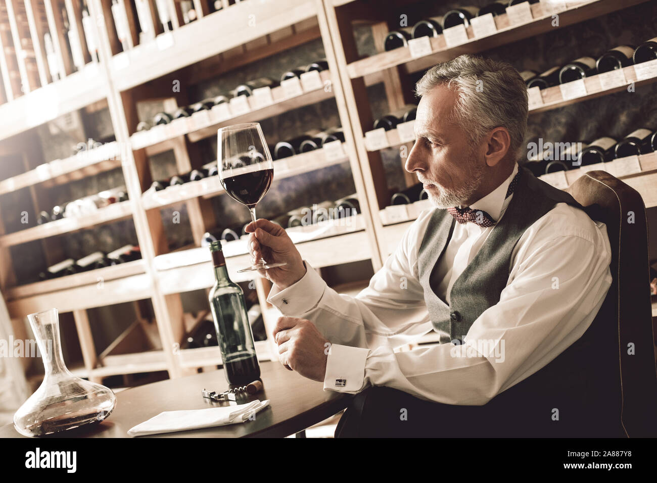 Sommelier Concept. Senior contrôle de sédiments dans le verre de vin rouge concerné Banque D'Images