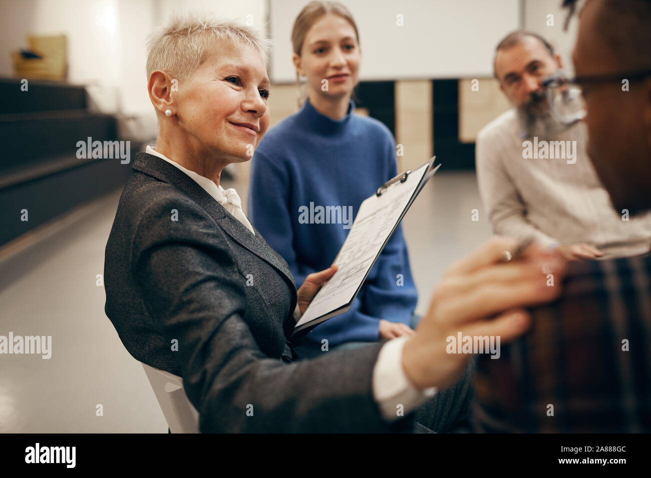 Femme mature avec de courts cheveux blonds à l'écoute de jeune homme très attentivement pendant la thérapie leçon Banque D'Images