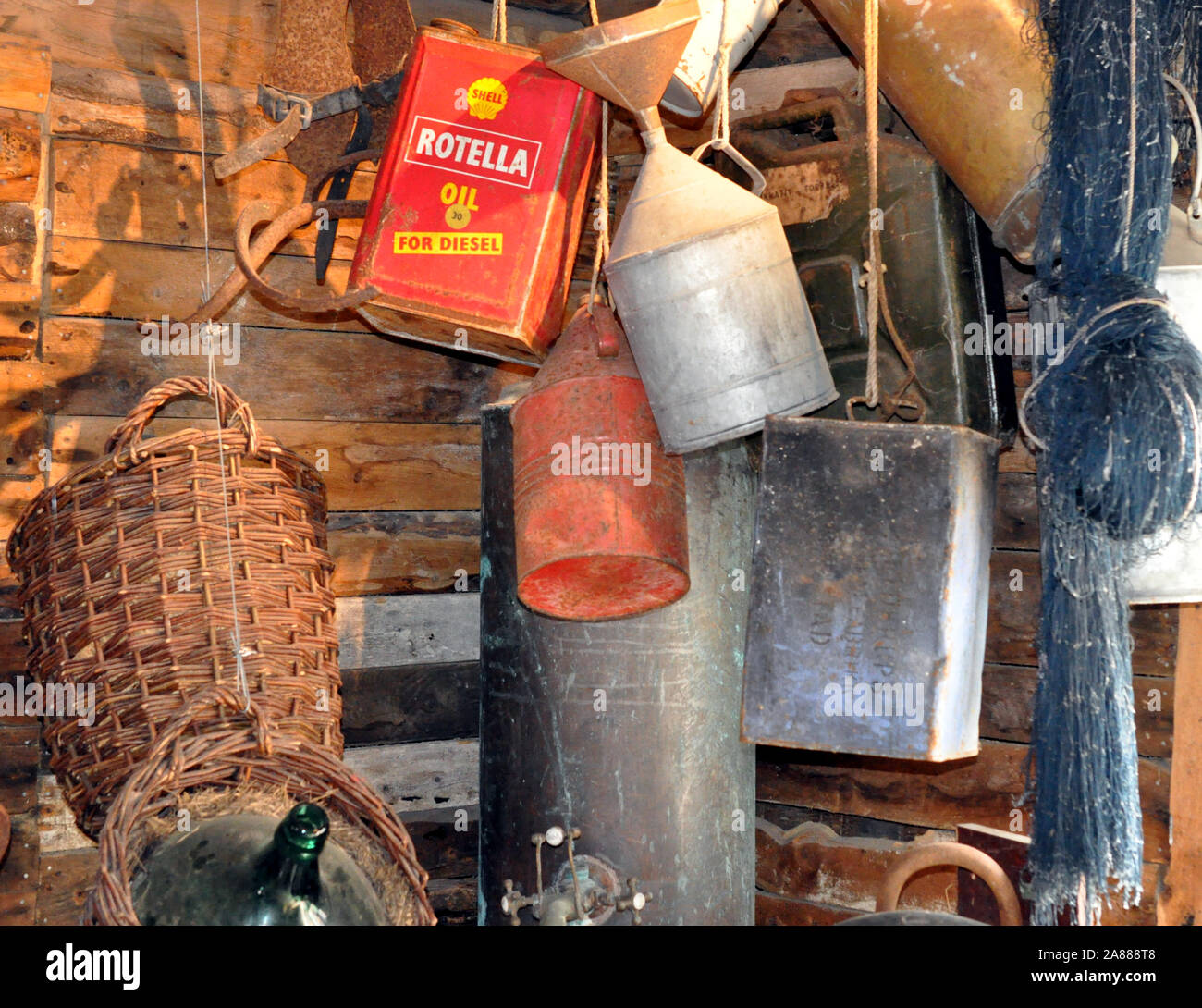 Une collection de vieux bidons d'huile, y compris l'huile Shell Rotella par pendaison, dans une cabane en bois. Banque D'Images