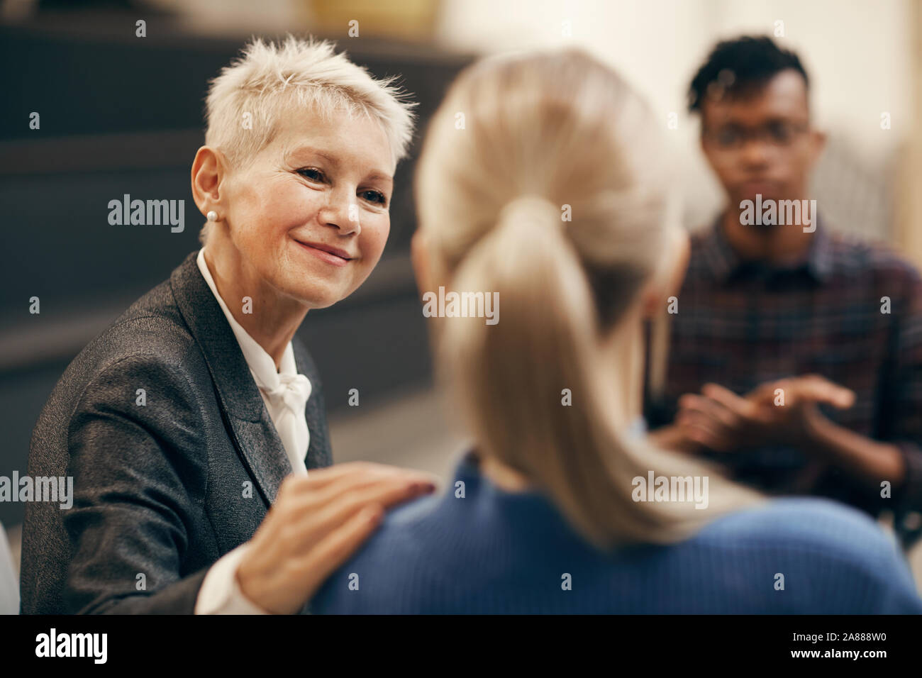 Femme mature avec de courts cheveux blonds à parler aux jeunes pendant la formation leçon Banque D'Images