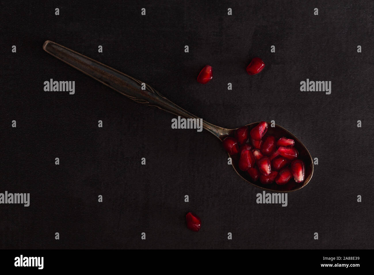 Fruits grenade fraîche avec des graines rouges sur cuillère dans un paysage sombre. Banque D'Images