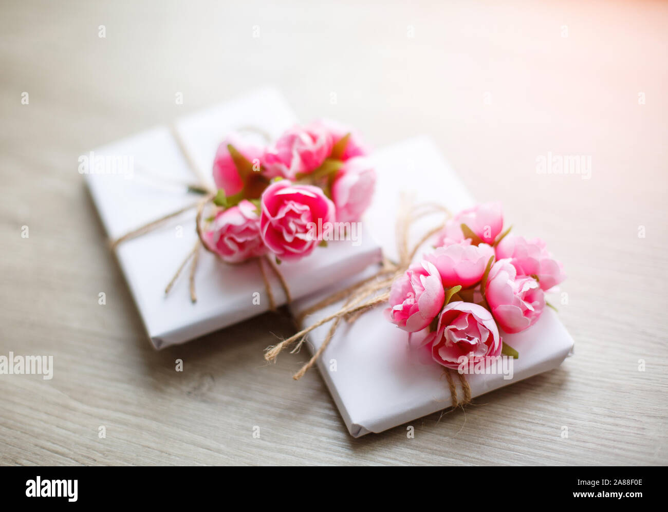 Boîte cadeau de style naturel fabriquée à la main sur une table en bois. Boîte cadeau faite à la main, enveloppée de papier blanc. Éléments de décoration à motifs floraux. Banque D'Images