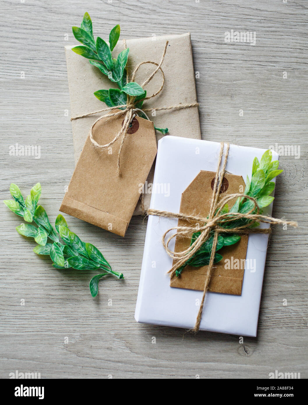 Composition avec boîtes cadeaux de style naturel artisanales, éléments de décoration florale et noeud de ficelle rustique sur fond en bois. Banque D'Images