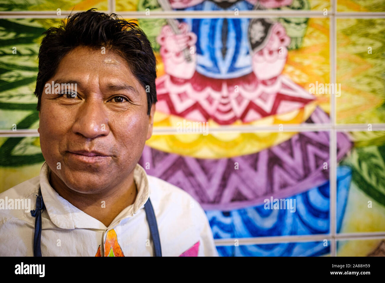 Portrait de l'artiste autochtone Aymara Roberto Mamani Mamani avec l'un de ses tableaux dans sa galerie dans le quartier historique de La Paz, Bolivie Banque D'Images