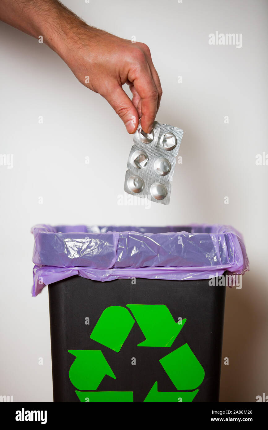 Mettre la main dans le bac de paquets médecine expiré avec signe de recyclage pour une élimination sécuritaire. Personne séparant les déchets dangereux. La gestion des déchets médicaux Banque D'Images