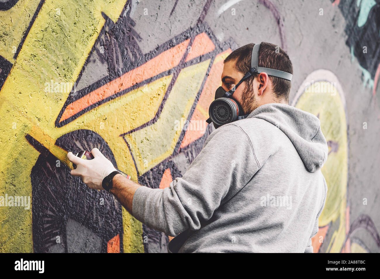L'artiste graffiti de rue avec une peinture aérosol couleur un graffiti sur le mur de la ville, le mode de vie urbain - concept art de rue Banque D'Images