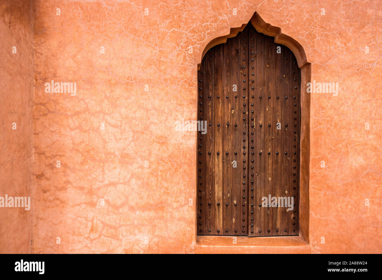 Maroc, Marrakech. Les jardins de la Menara. Détail architectural sur une porte en bois sur un mur dans l'ocre. Banque D'Images