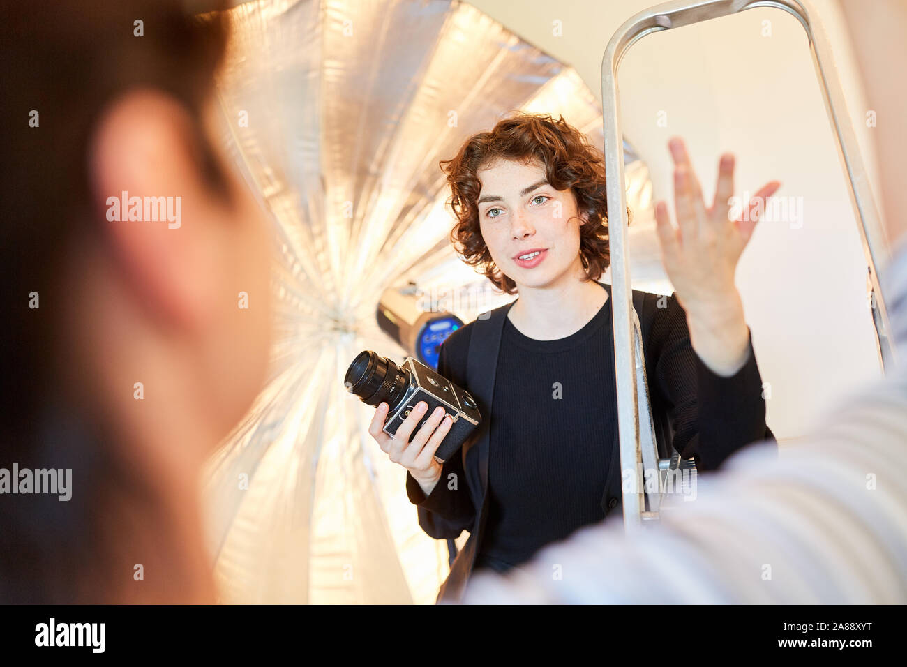 Photographe avec appareil moyen format discute avec un collègue dans le studio photo Banque D'Images