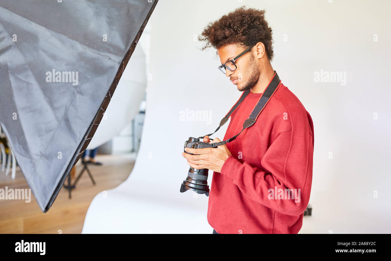 Jeune photographe professionnel avec appareil photo dans son studio photo Banque D'Images