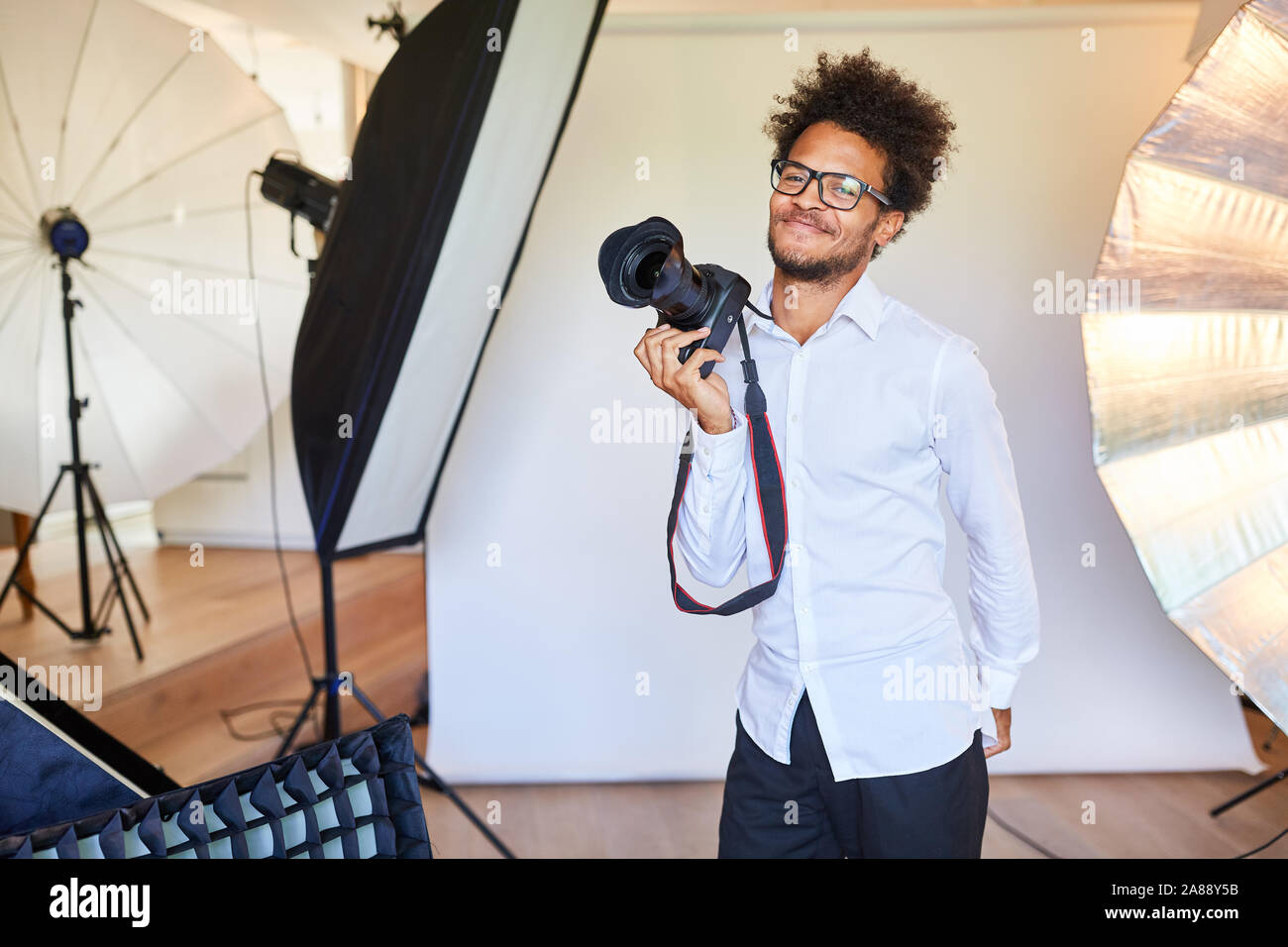 Jeune photographe créatif dans le studio photo avec l'appareil photo reflex Banque D'Images