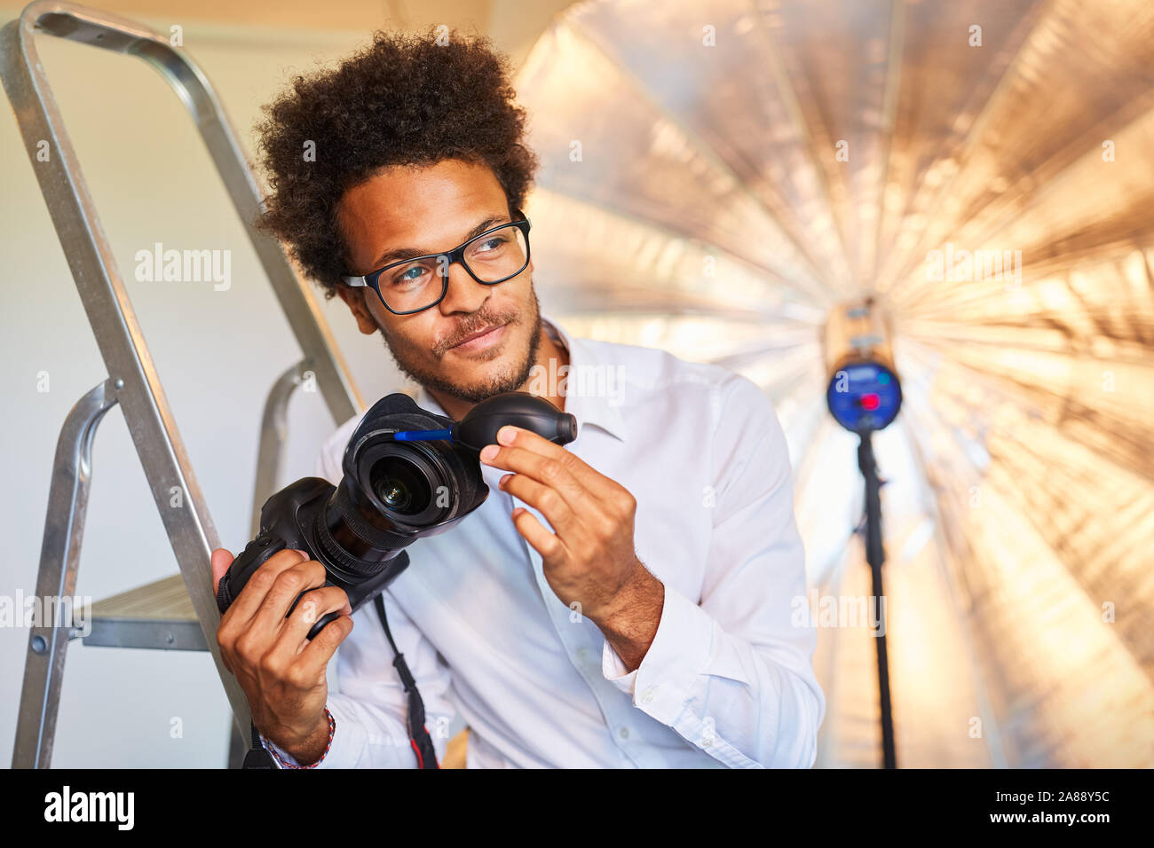 Le jeune photographe ou photo à l'assistant de nettoyage de l'objectif de la photo studio Banque D'Images