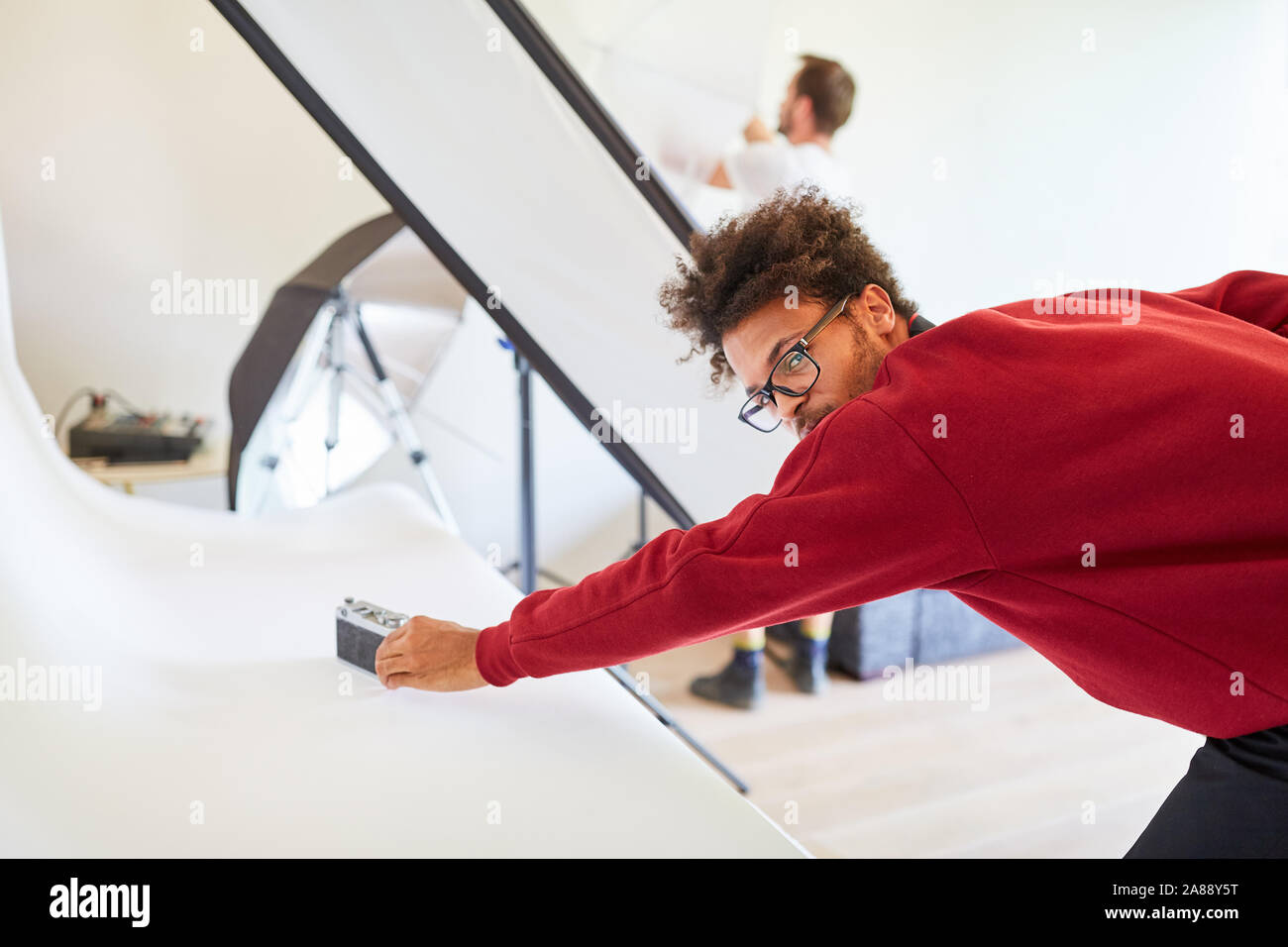 Le jeune photographe ou photo assistant dans le studio photoshoot prépare Banque D'Images