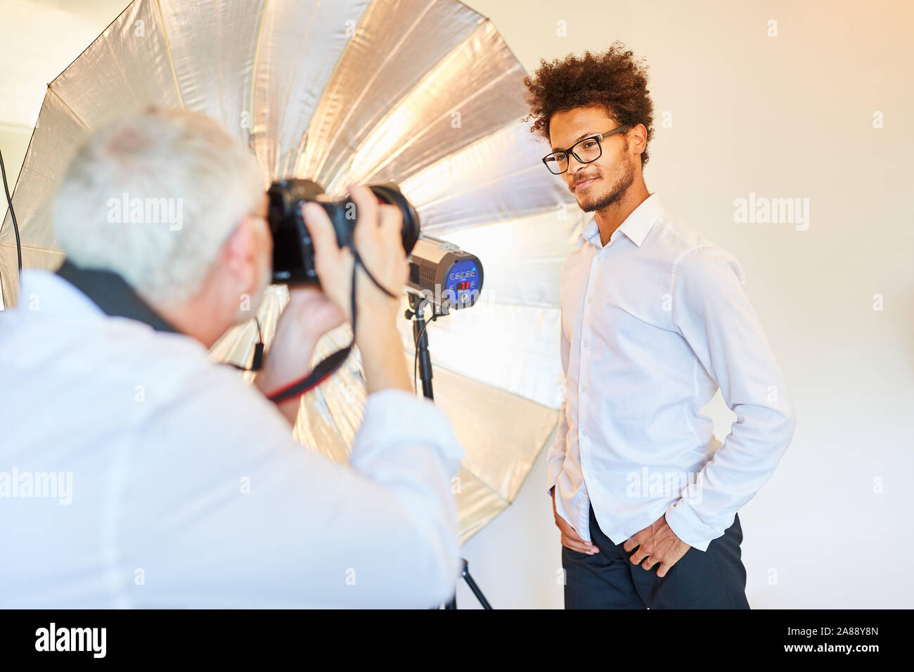 Jeune homme comme un modèle avec le photographe dans le studio photo pendant la séance photo Banque D'Images