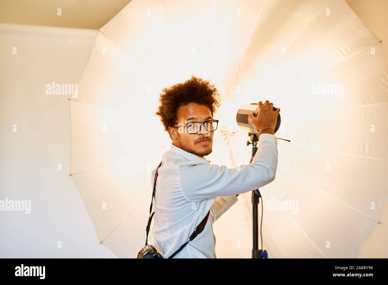 Le jeune photographe avec studio light et lampe à l'éclairage de studio Banque D'Images