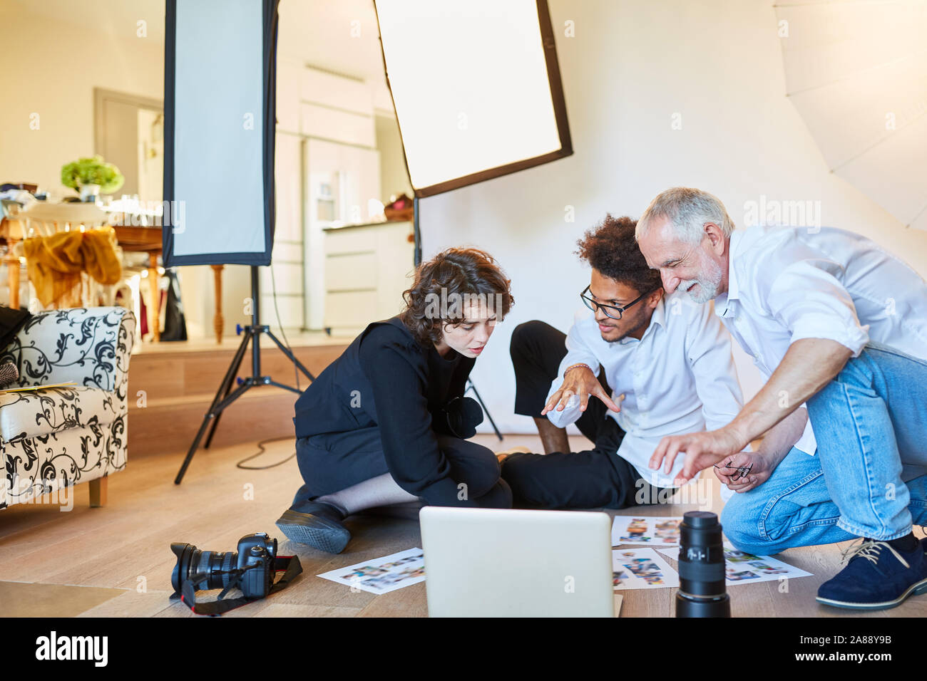 Photo photographe avec assistant et directeur artistique à la sélection de photos dans le studio photo Banque D'Images