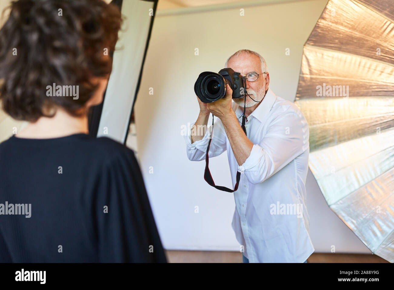 Photographe expérimenté avec appareil photo numérique prend des photos dans le portrait photo studio Banque D'Images