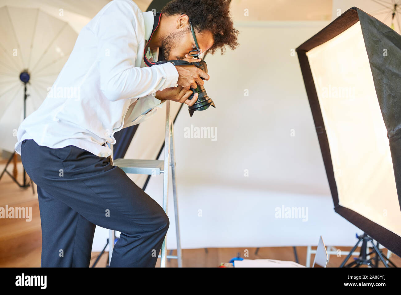 Jeune photographe créatif avec caméra à la séance photo dans le studio photo Banque D'Images