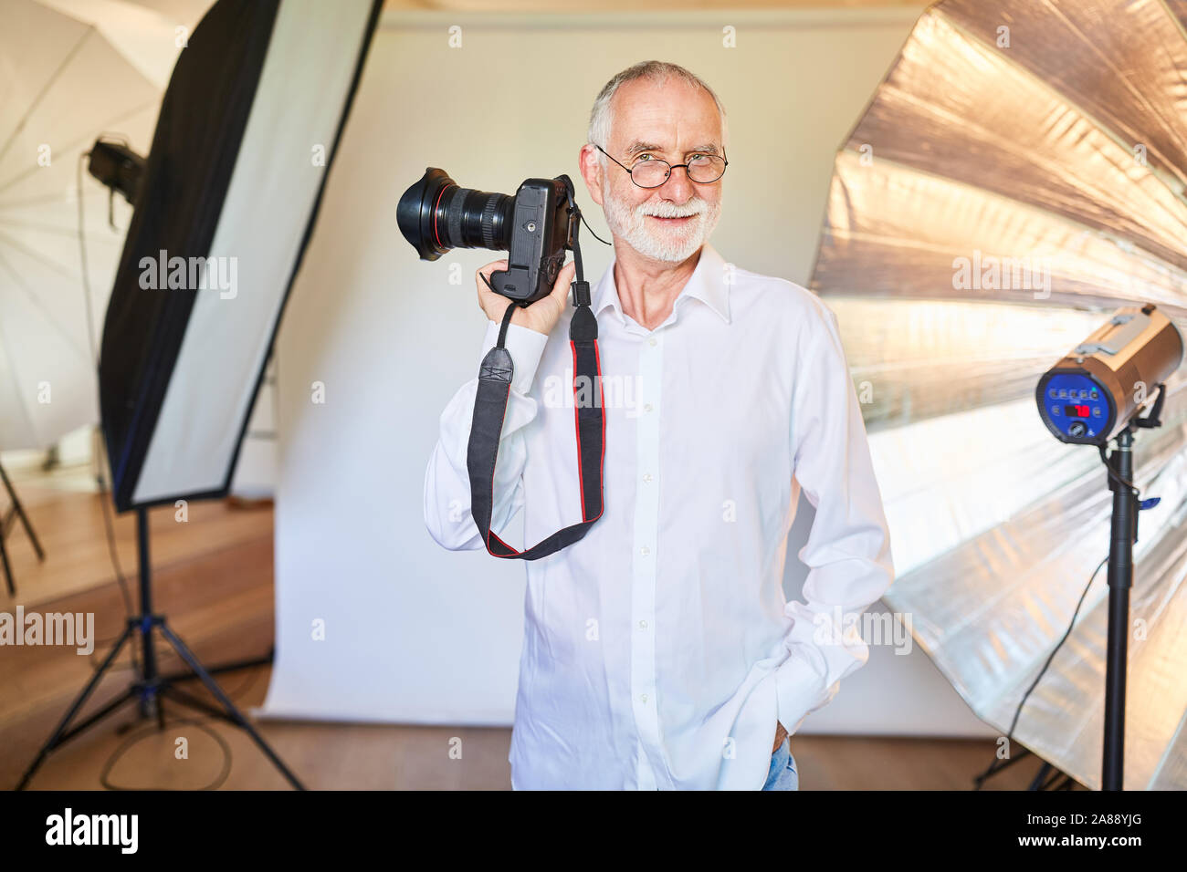 Photographe expérimenté avec caméra dans le studio photo en face de projecteurs Banque D'Images