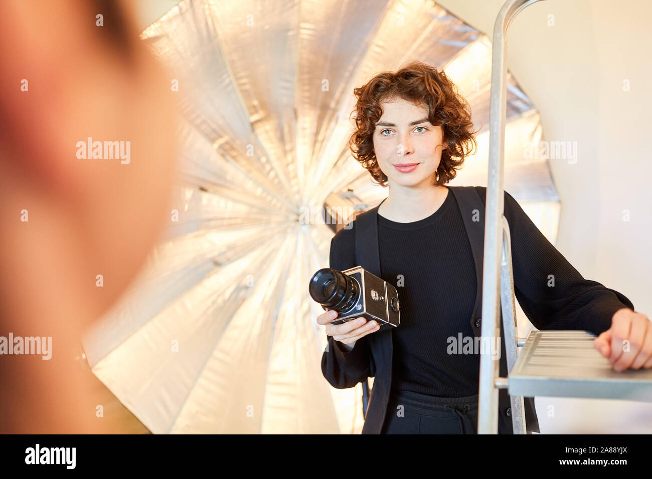 Le jeune photographe avec appareil photo de format moyen dans le studio photo pendant la séance photo Banque D'Images