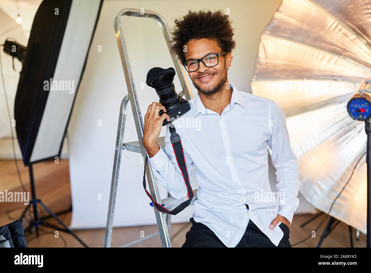 Jeune homme avec succès en tant que photographe dans le studio, avec un appareil photo Banque D'Images