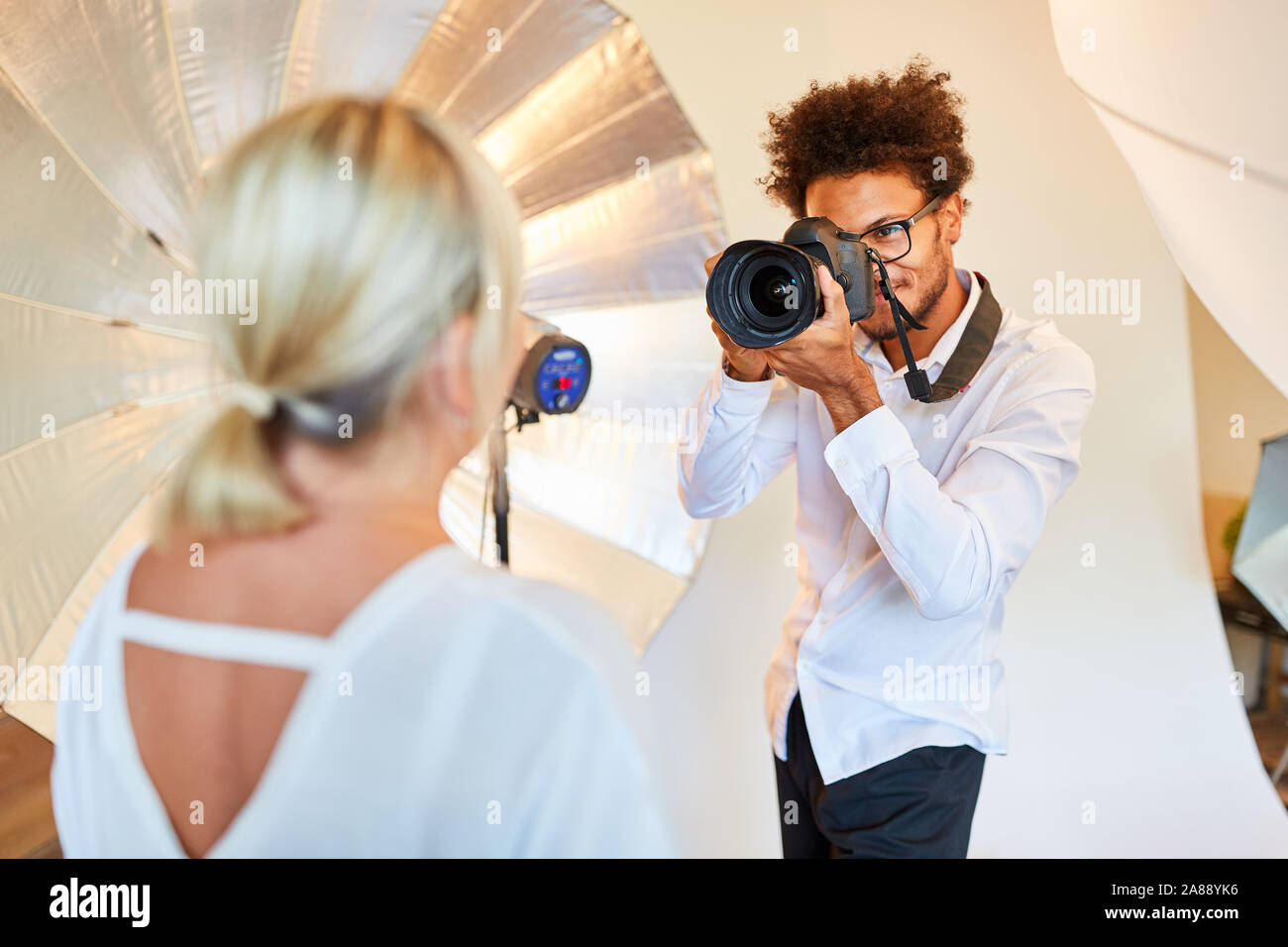 Photographe avec appareil photo prend des photos portrait d'une femme dans la photo studio Banque D'Images