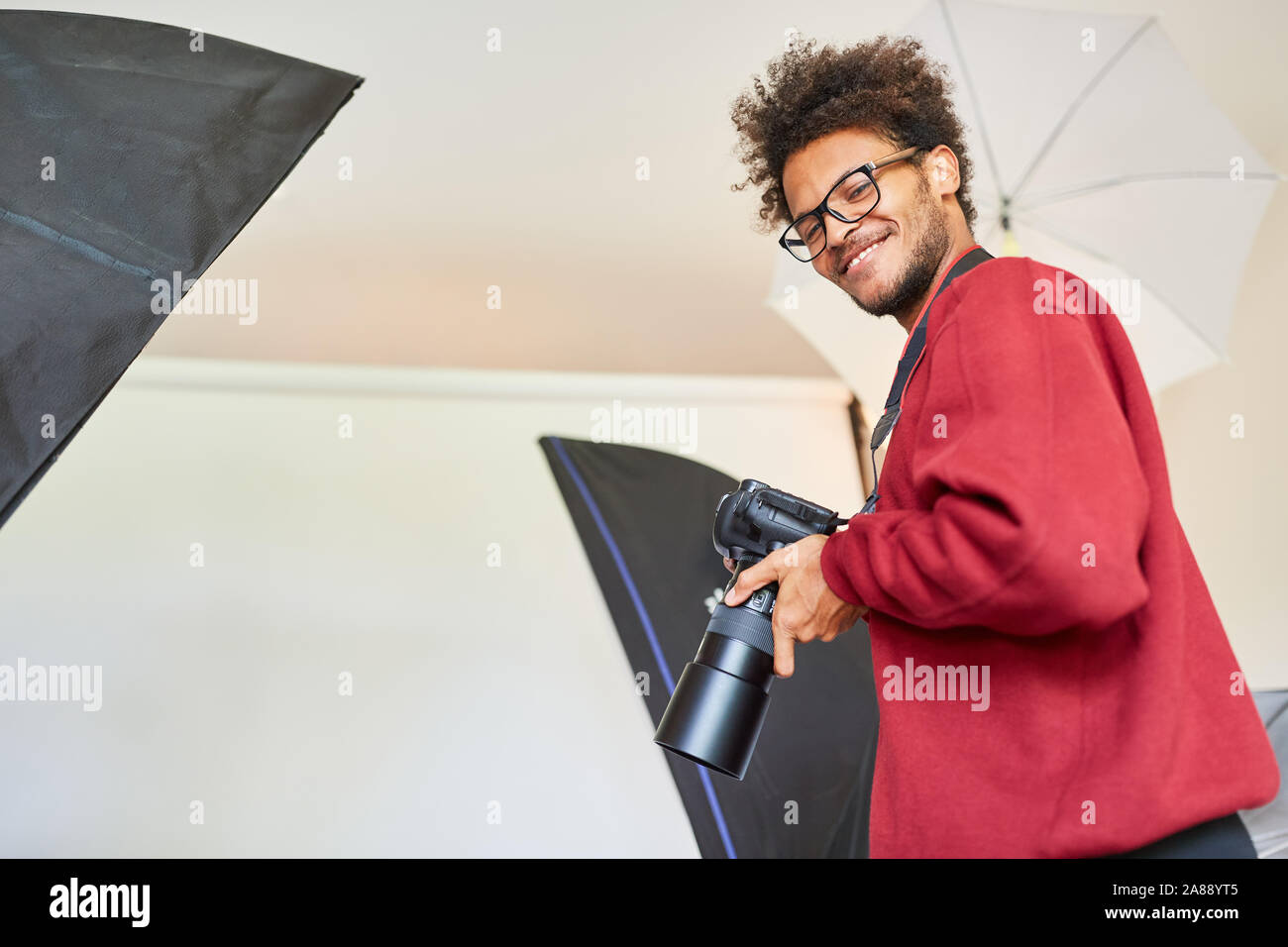 Jeune homme comme un photographe professionnel avec caméra dans le studio photo Banque D'Images