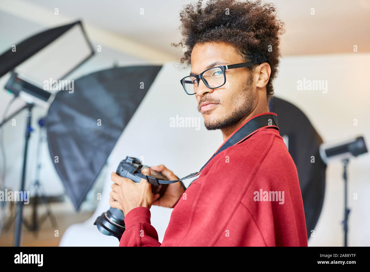 Cool le jeune photographe en tant qu'entrepreneur dans son studio, avec un appareil photo Banque D'Images