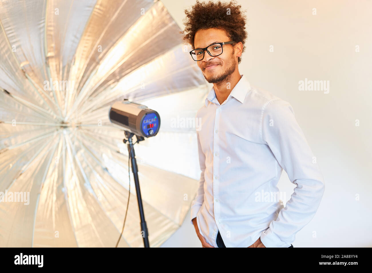 Jeune homme comme un modèle ou un photographe en face de lampe torche avec studio Banque D'Images