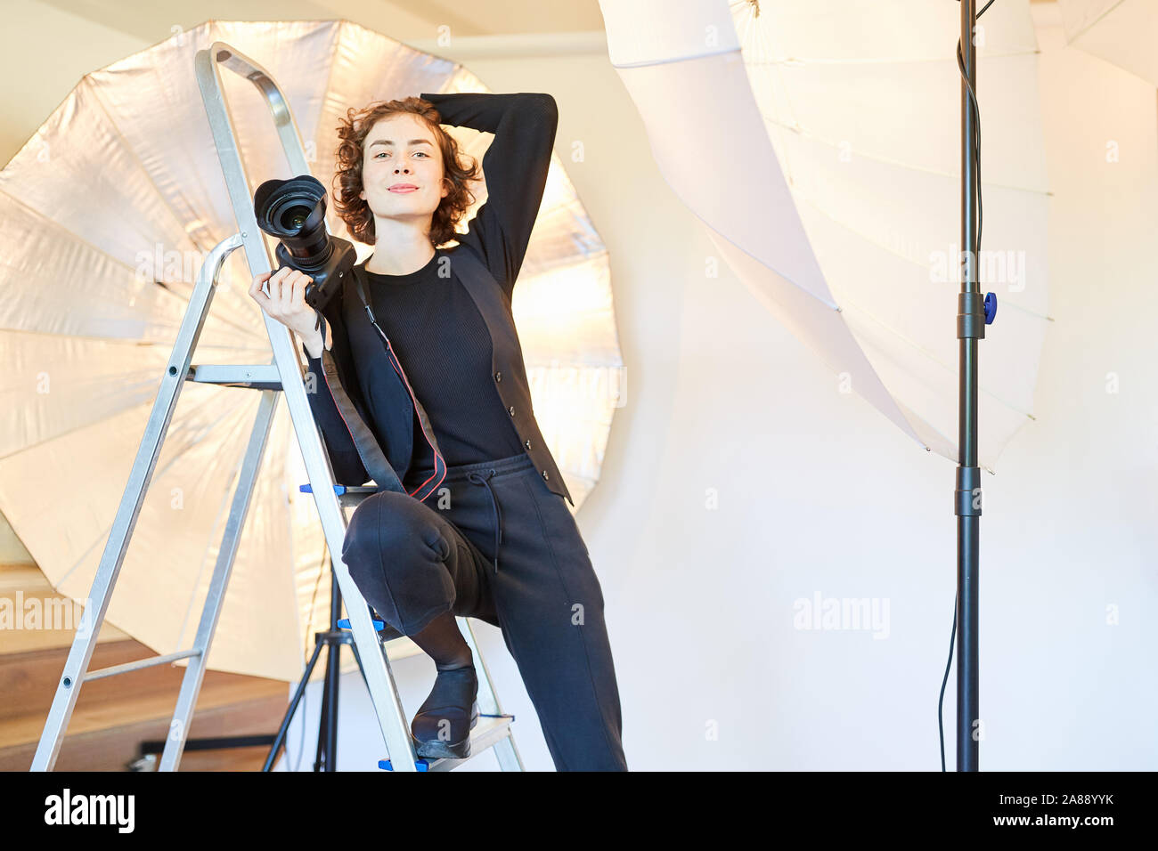 Jeune femme en tant que photographe indépendant dans son studio de photo avec un appareil photo numérique Banque D'Images