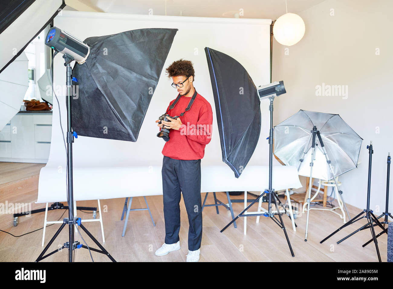 Photographe ou étudiant studio photo entre feux dans son studio photo Banque D'Images