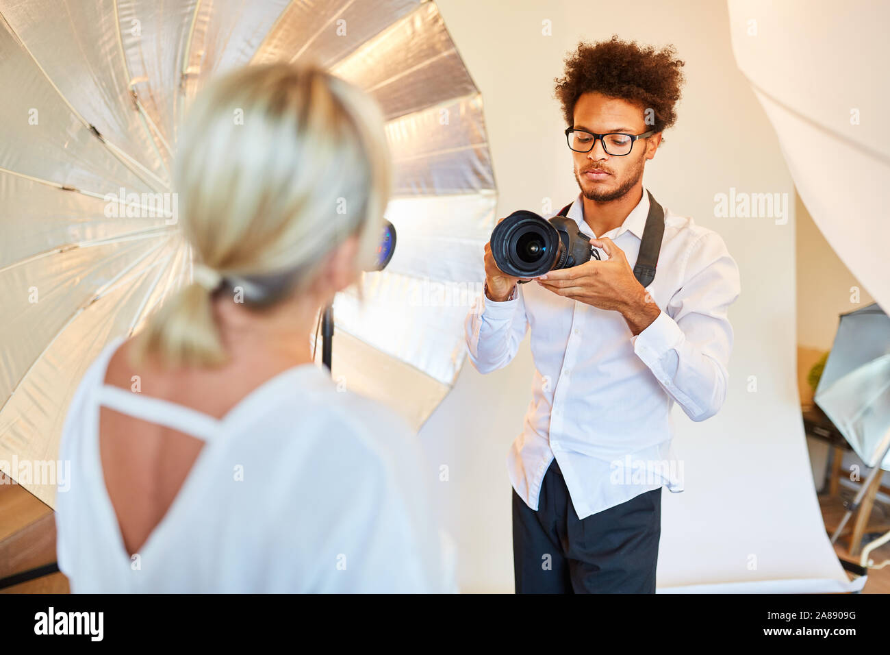 Le jeune photographe prend des photos portrait d'une femme comme modèle pour la photo studio Banque D'Images