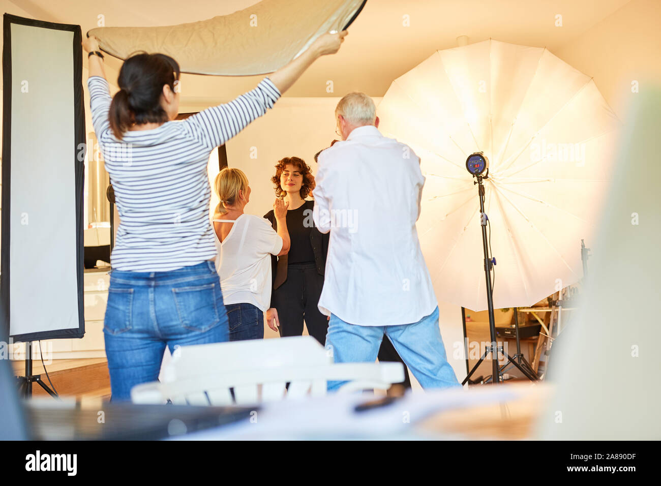 Modèle avec l'équipe de photographe et maquilleuse dans le studio photo pendant la séance photo Banque D'Images