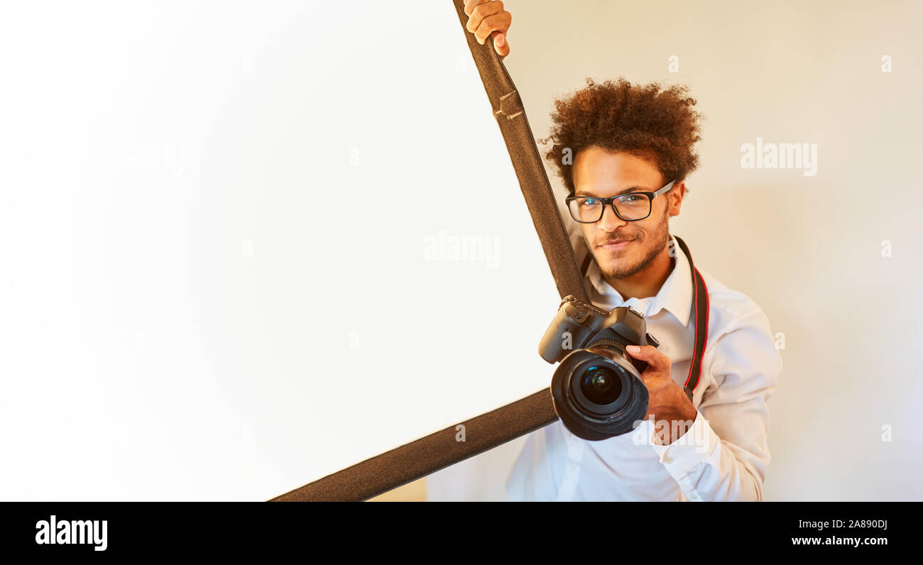 Jeune photographe avec appareil photo numérique dans son studio photo Banque D'Images